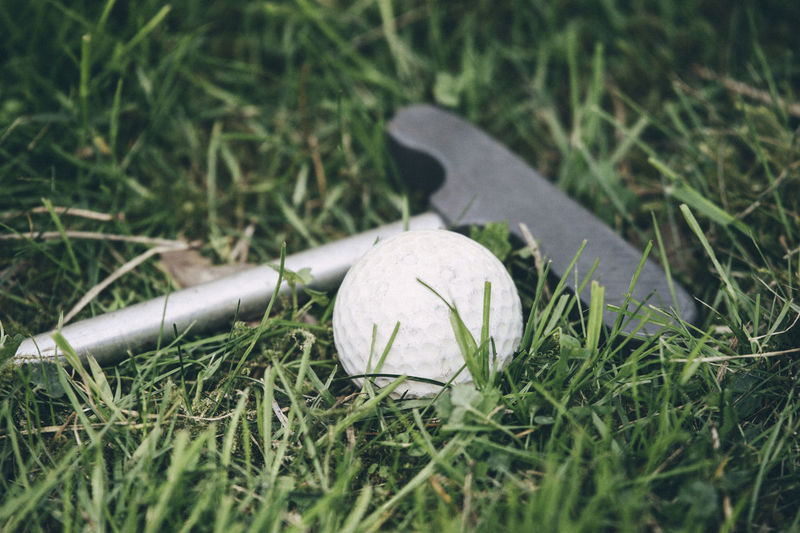 Close-up of golf club and golf ball on grass