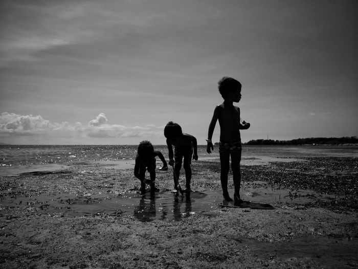 Children on beach against sky