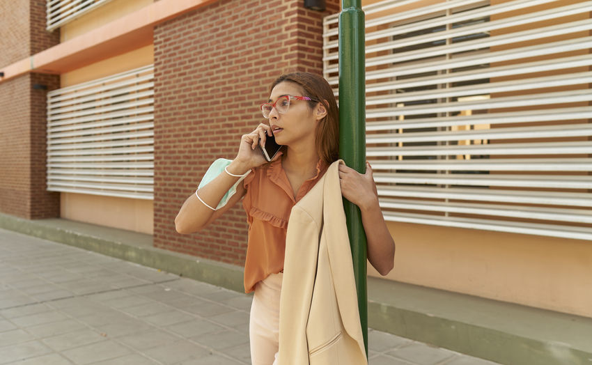 Young business woman talking on her cell phone outside commercial building