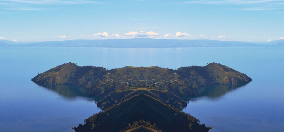 Scenic view of sea by mountains against sky