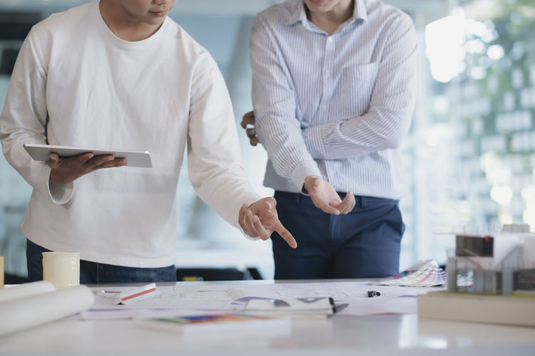 Midsection of colleagues discussing at desk in office