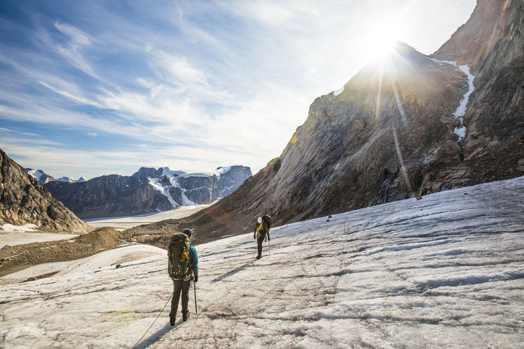 Backpackers crossing a glaciated mountain on baffin island.