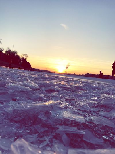 Scenic view of frozen lake against sky during sunset