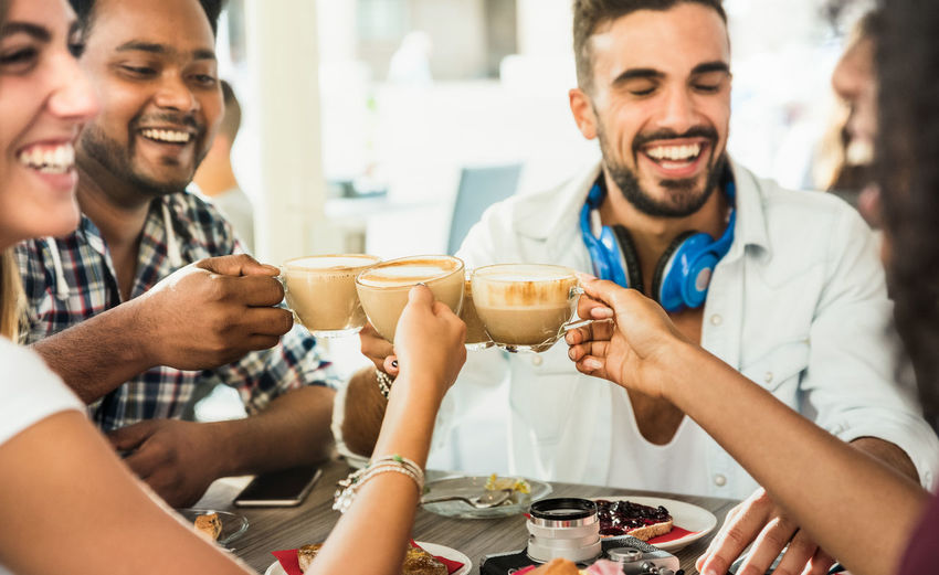 Happy friends toasting coffee in cafe