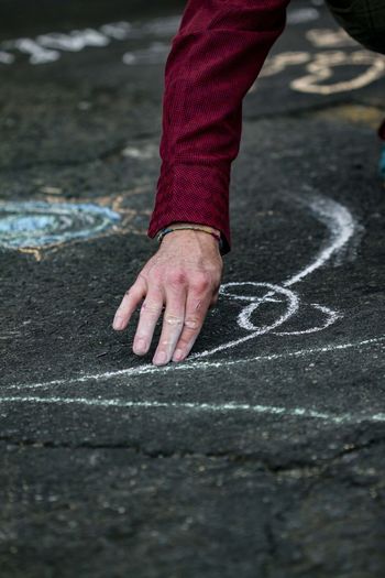 Cropped hand of man chalk drawing on road