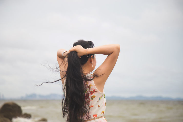 Midsection of woman standing on beach against sky