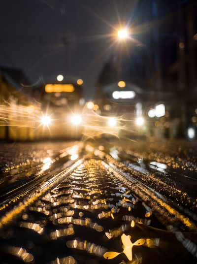 Illuminated railroad tracks on city street at night