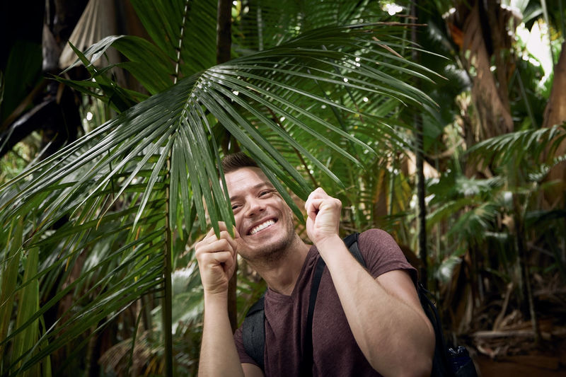Happy man discovering jungle. funny portrait of traveler in tropical rainforest in seychelles.