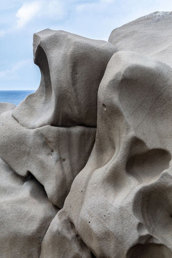 Close-up of rock formation on beach against sky
