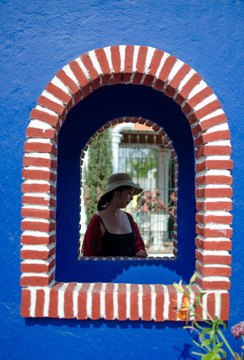 Young woman wearing hat seen through arch window