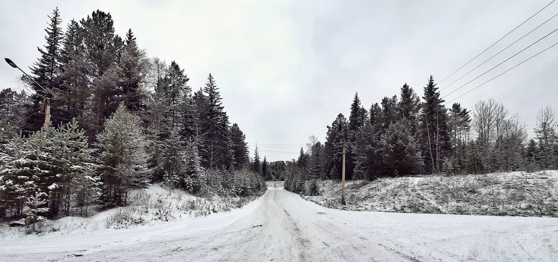Panoramic view of snow covered road against sky
