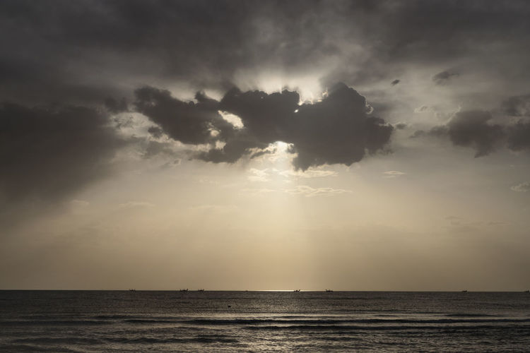 Beautiful sun rays behind the clouds at the sea ,on the horizon fishing boats