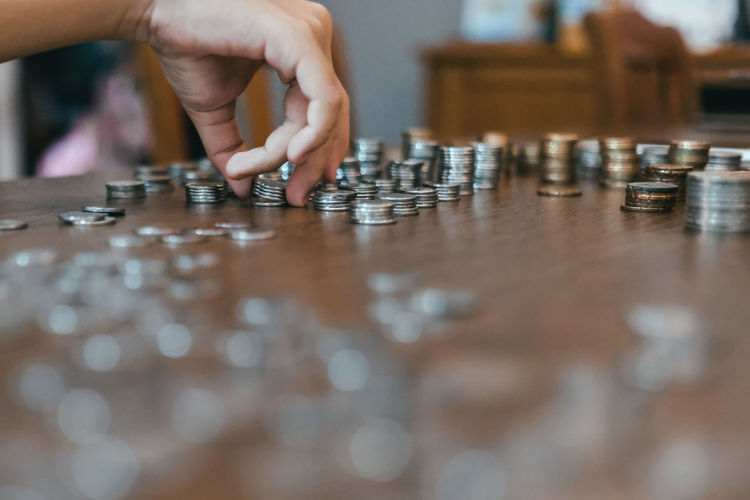 Cropped hand of person stacking coins on table