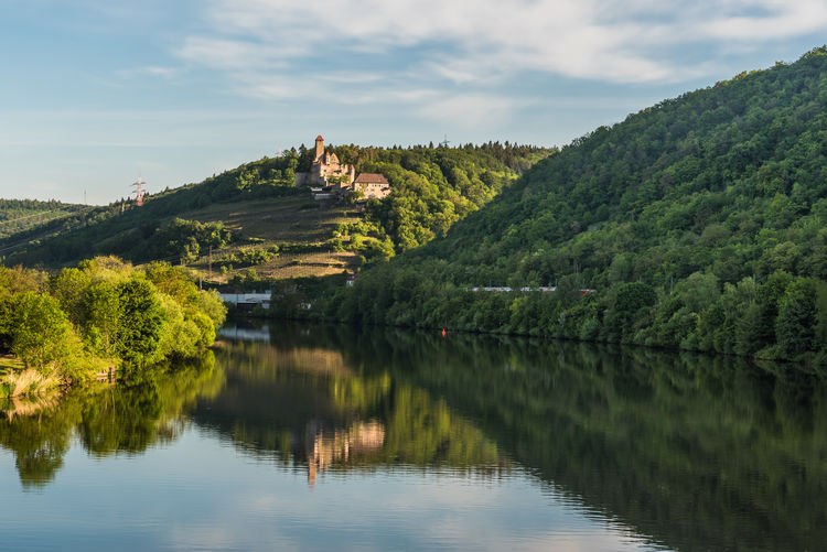 Scenic view of neckar river with castle on a hill against sky 