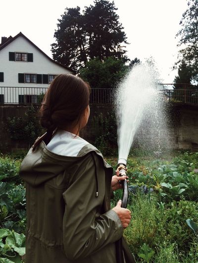 Rear view of woman watering garden