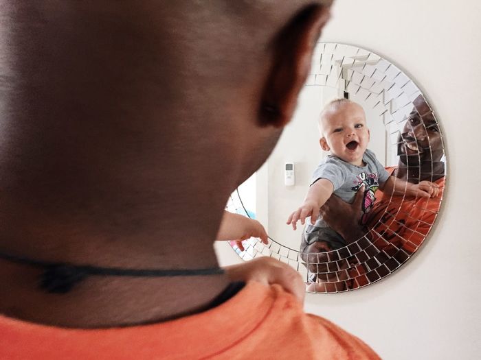 Reflection of man and baby boy in mirror at home