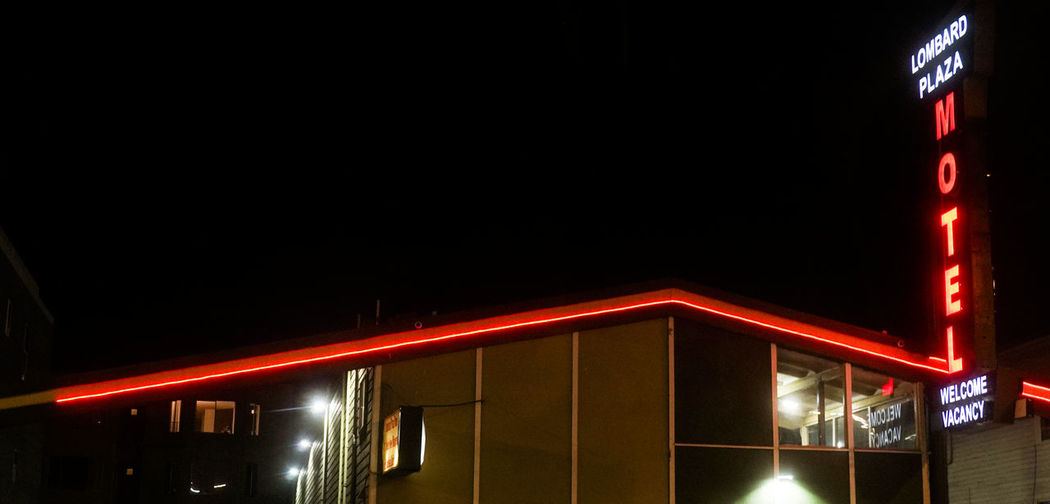 Low angle view of illuminated motel against clear sky at night