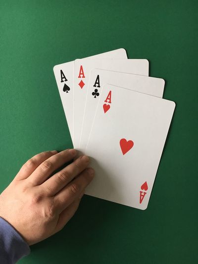 High angle view of man with aces cards on green table
