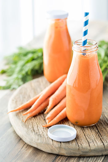 Close up of two bottles of freshly made carrot juice ready for drinking.
