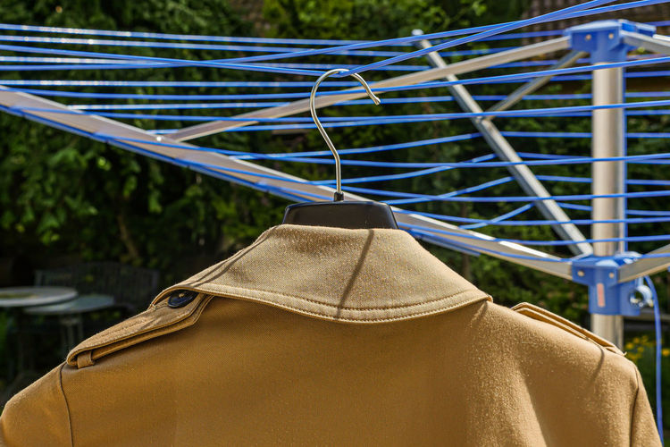 Beige winter coat hang drying on outdoors clothesline. closeup of collar.