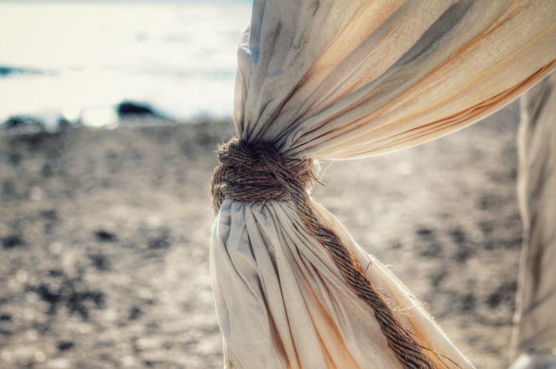 Close-up of rope tied on curtain at beach