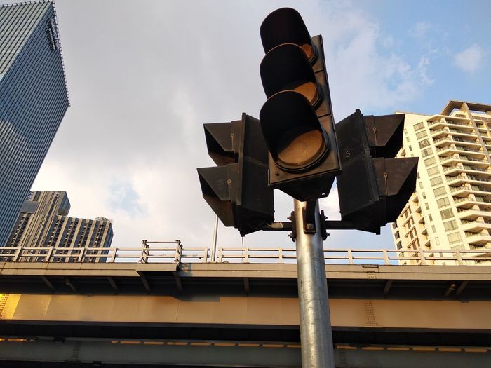 Low angle view of traffic light and bridge against sky