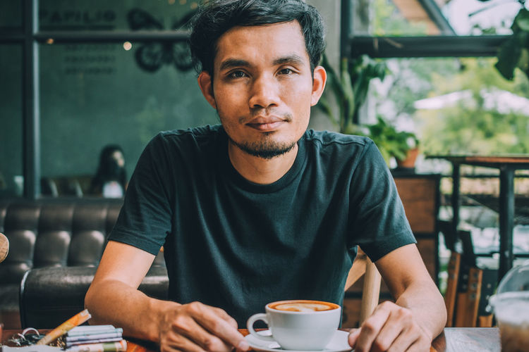 Portrait of young man with coffee cup in restaurant