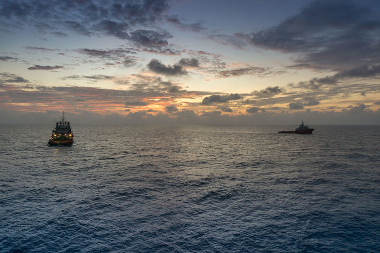 Anchor handling tugboats maneuvering during sunrise at offshore terengganu oil field