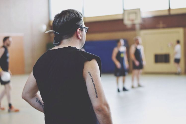 Rear view of man with players in background at basketball court