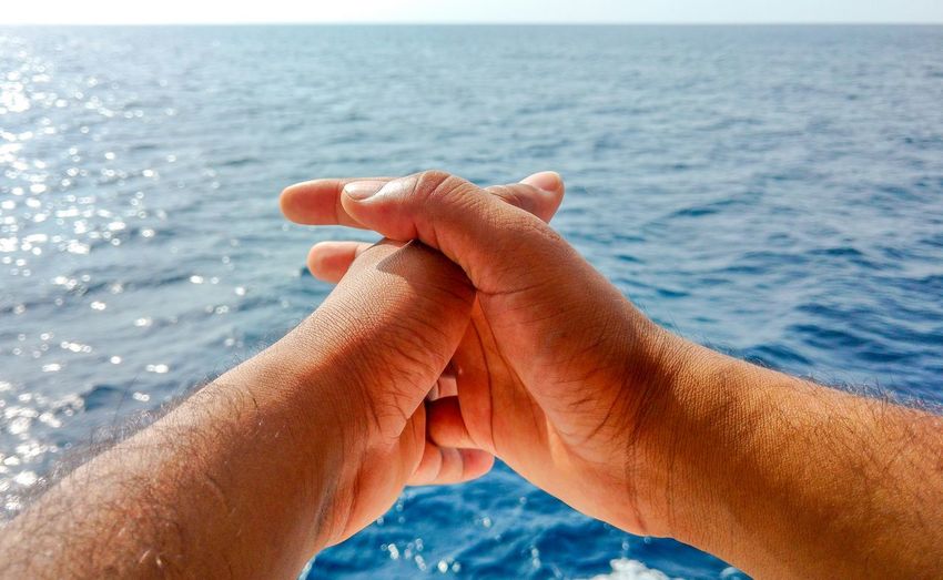 Close-up of man hands with sea in background. man in a thinking position 