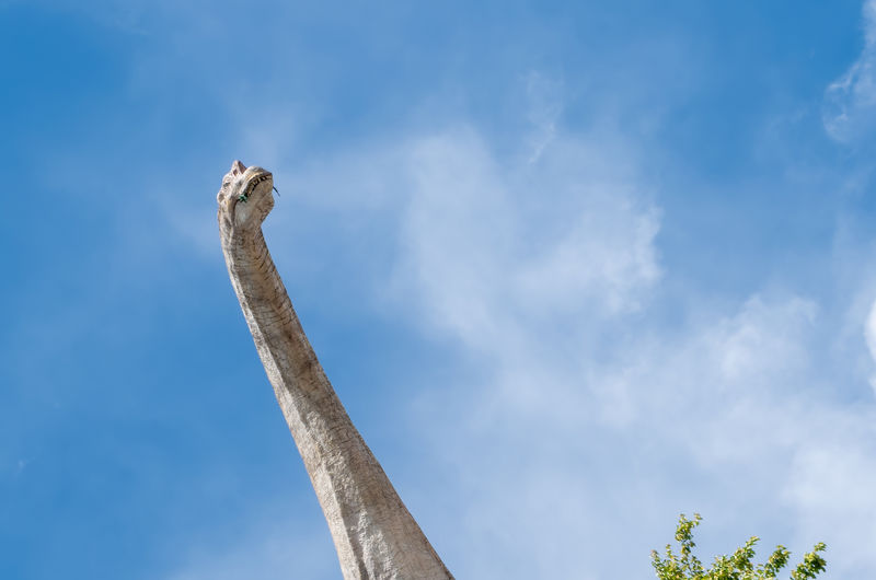 Low angle view of dinosaur against blue sky