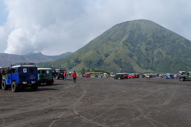Vehicles on ground against mountains