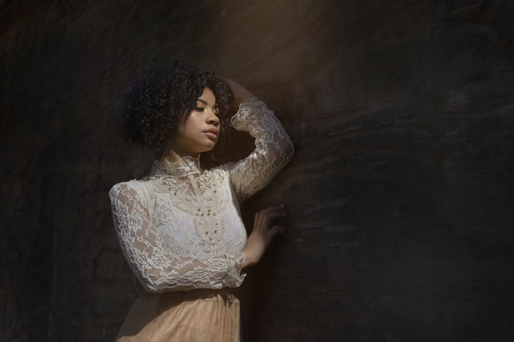 Portrait of a young african american woman next to a wooden wall