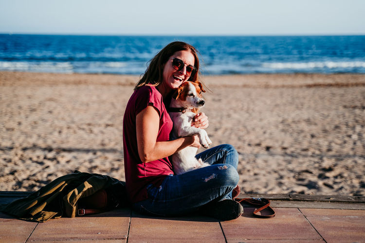 Young woman with dog sitting on beach