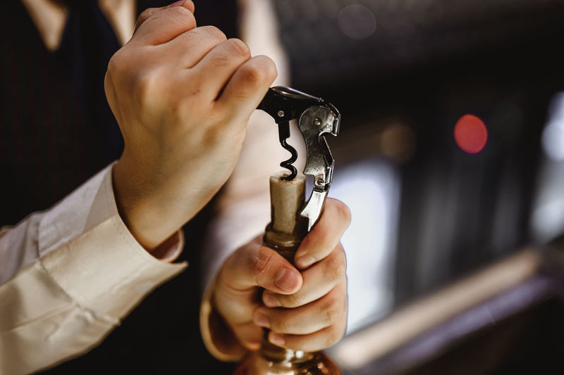 Midsection of man holding wine opener