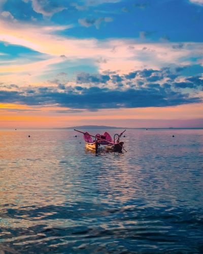Boat in sea against sky during sunset