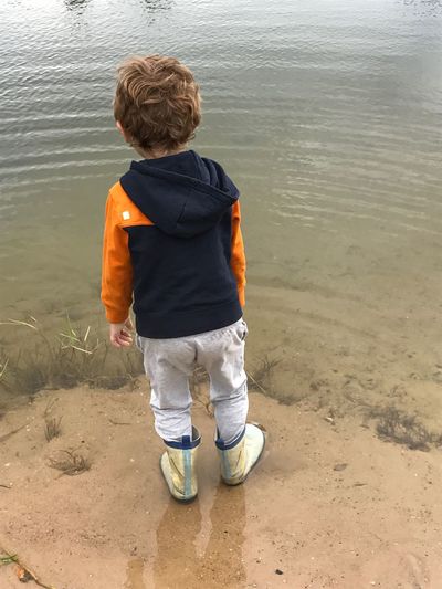 Rear view of boy standing in water at lake