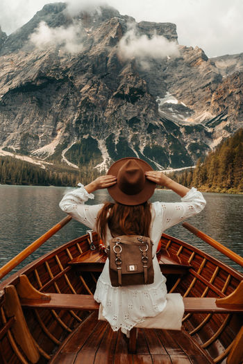 Rear view of woman in boat in lake against mountains