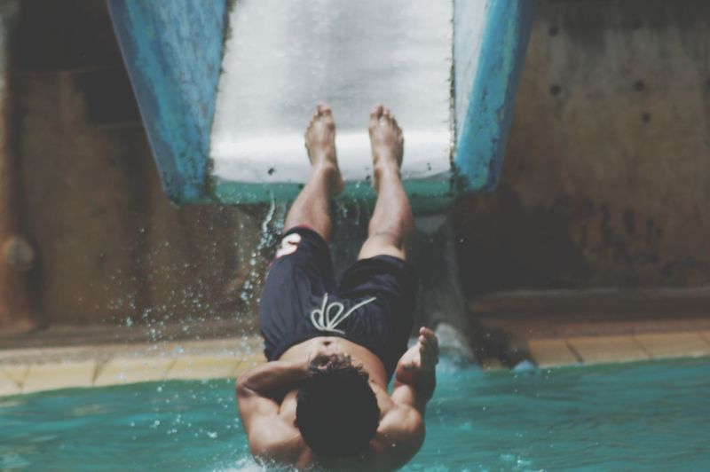 Shirtless man enjoying slide at water park