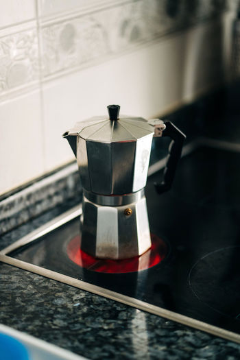 Metal stove top coffee maker with plastic handle on modern hot hob in house kitchen in daylight