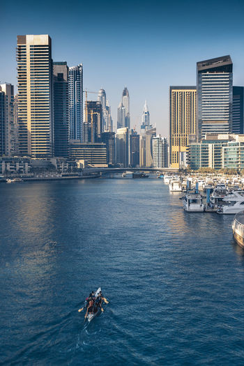 High angle view of boat moving on river amidst modern buildings in city