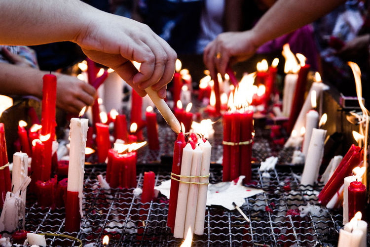 People lighting bunch of candles