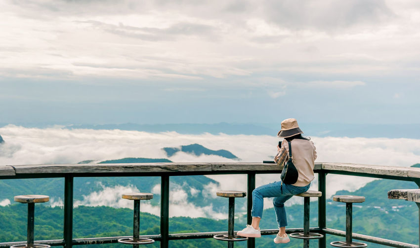 Woman sitting on wooden balcony looking at mountain and fog view travel