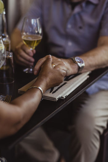 Cropped image of couple holding hands over table in cafe