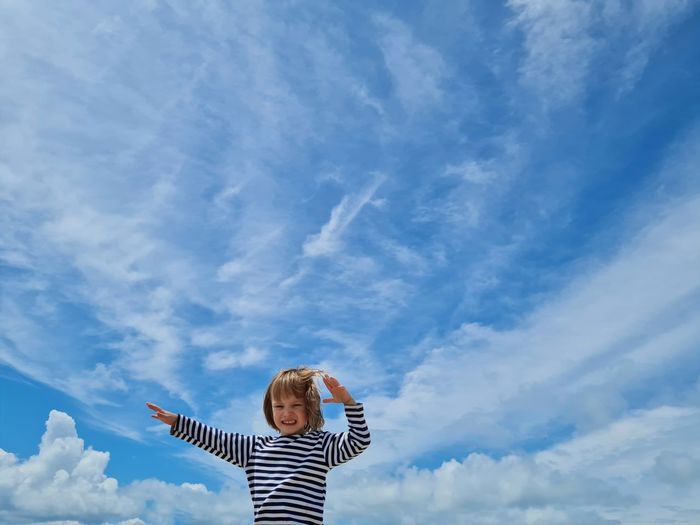 Low angle view of woman standing against cloudy sky