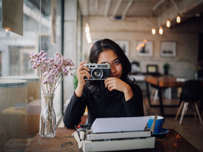 Woman photographing with camera at table in cafe