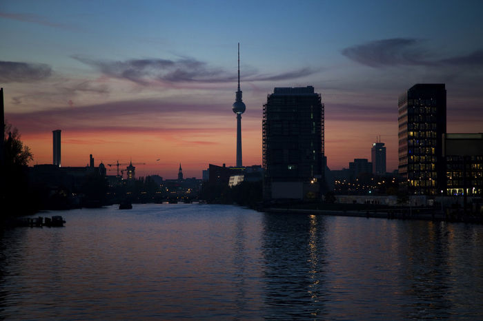 River by fernsehturm against sky during sunset