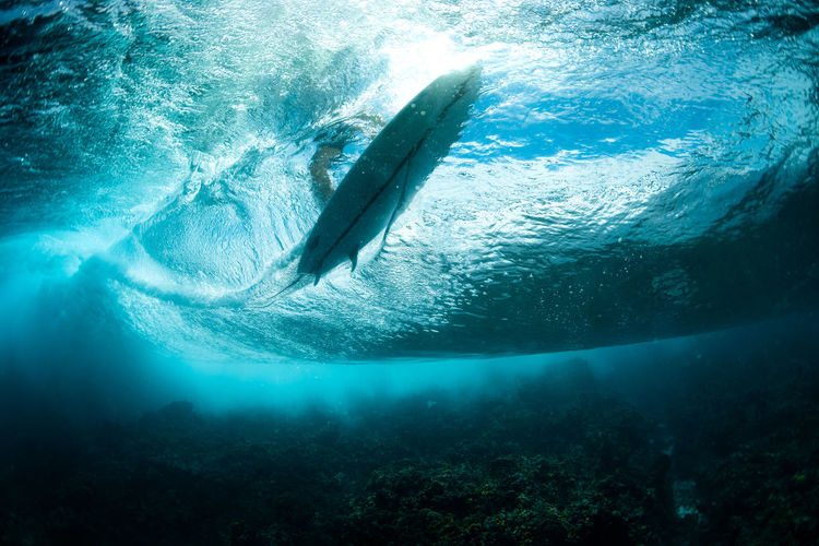 Underwater view of a surfboard in a clear wave
