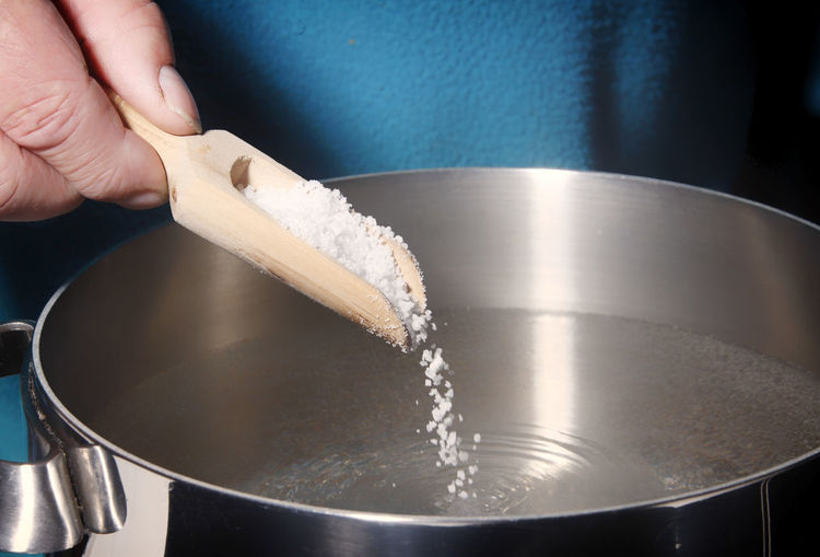 Midsection of person adding salt in water
