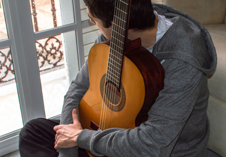 Midsection of man playing guitar at window
